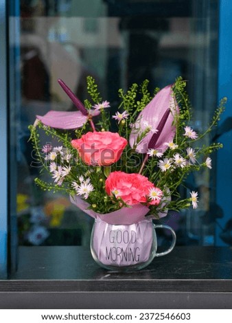 A bouque of flowers in a glass bowl with good morning written on it