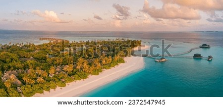 Aerial sunset of beautiful Maldives paradise tropical beach. Amazing colorful sea sky bay water, palm trees sandy beach. Luxury villas resort, travel vacation destination. Best popular landscape view
