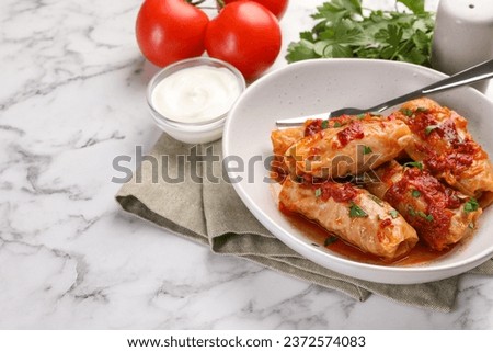 Delicious stuffed cabbage rolls cooked with homemade tomato sauce on white marble table, closeup. Space for text Royalty-Free Stock Photo #2372574083