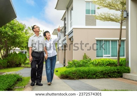 Asian old couple people buy new home from they savings after retirement, new house in village walking togater in garden Royalty-Free Stock Photo #2372574301