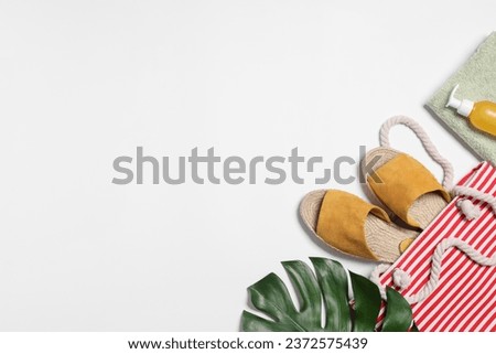 Flat lay composition with bag, green leaf and other beach accessories on white background. Space for text