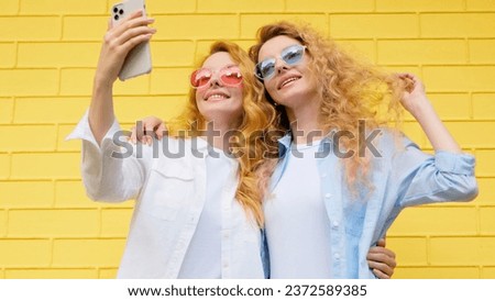 Selfie, friends, and woman posing with phone outside, peace sign for social media post. Two women sister, fashionable with mobile smartphone friendly smiling, taking cool profile picture on yellow