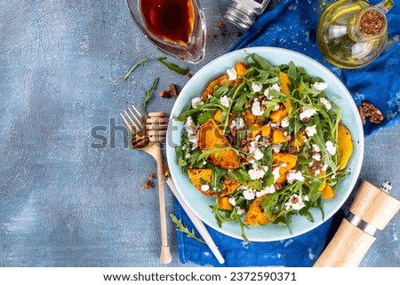Autumn warm salad. Homemade fall season salad with grill and baked pumpkin, arugula, feta cheese and crushed nuts, Whole vegan paleo fruit and vegetable salad idea.