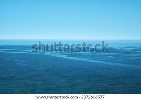 Dark blue water from the sea with blue sky. Vertical format, also suitable as a poster or background. Free space for text or objects.