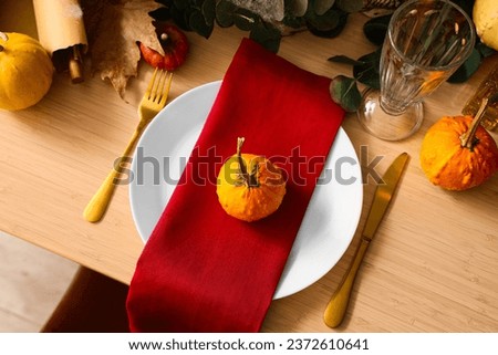 Festive table setting with pumpkins and golden cutlery for Halloween party, closeup