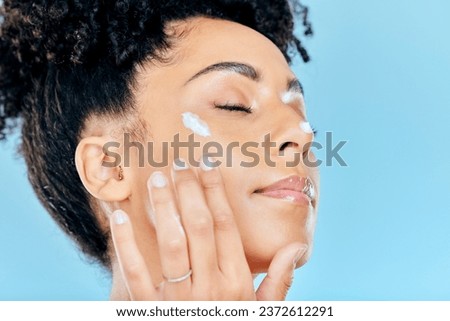 Beauty, face and relax woman with cream application of ointment, lotion or collagen for skin hydration, wellness or spa skincare. Eyes closed, anti aging routine and studio model on blue background