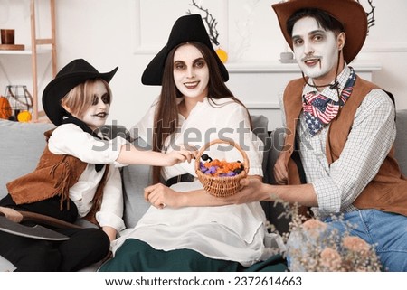 Happy family with candies celebrating Halloween at home