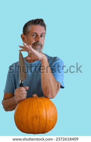 Isolated pumpkin picture, Man holds a sharp knife with a menacing smile, he's about to carve the squash for his recipe in the kitchen. Bright blue and orange capture with copy space.