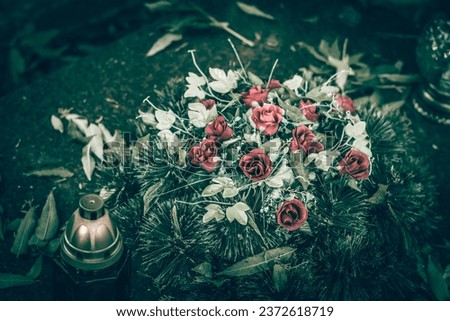 grave decorated with lantern, candles, chrysanthemum flowers during All souls day, sad and peaceful atmosphere