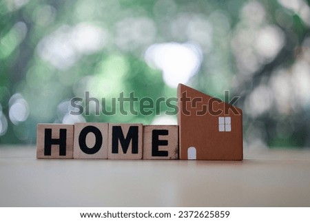 Wooden block with the word HOME and small wooden houses model on wood table. Dream house, home of love