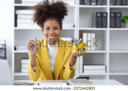 Businesswoman, real estate agent, is offering a house for sale with keys and persuades to sign a house purchase contract.