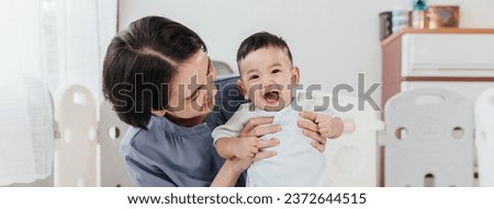 Asian mom lifting and playing newborn baby. Happiness Asian mother conference and playing with adorable her son looking at camera. Happy asian family healthcare love together mother’s day concept.