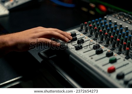 close-up shot of the male hand of a sound engineer switching settings on the mixing console for recording a soundtrack Royalty-Free Stock Photo #2372654273