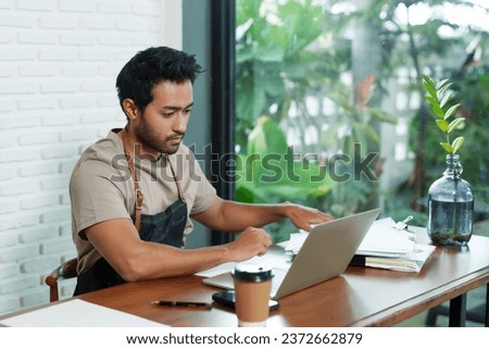 Multiethnic male business employee, cafe owner Sitting and working in front of a tablet and make documents for work on the side There was a disposable paper coffee cup next to it. Small family cafe