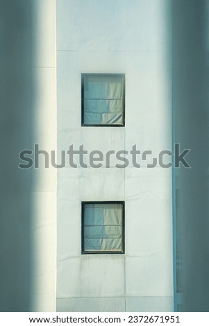 Picture of a window with curtains closed. The two windows of the building on opposite sides.