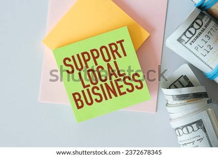 Support Local Business Text on Green Sticker attached to notepad with money dollars