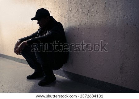 Man with trauma, shame or anxiety. Sad desperate young guy or teenage boy. Drug addiction or despair. Criminal outcast or homeless person with stress in dark. Silhouette of victim of discrimination. Royalty-Free Stock Photo #2372684131