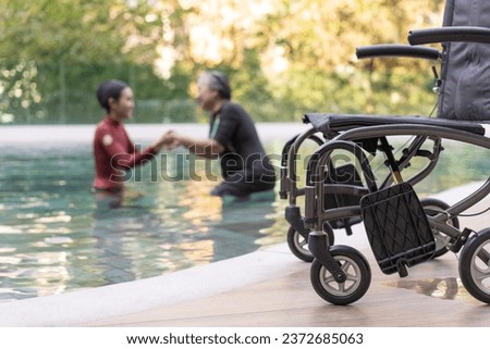 Selective focus off wheelchair background of physical therapist helping senior woman in aqua, old women and mature doing aqua aerobics exercise in swimming pool, Elderly sports, and active lifestyle. Royalty-Free Stock Photo #2372685063