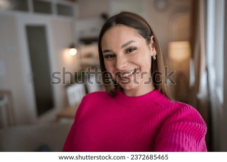 Front view portrait of one caucasian woman young female stand in her apartment at home wear sweater happy confident real people copy space UGC selfie user generated content happy smile Royalty-Free Stock Photo #2372685465