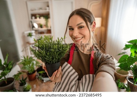 One woman young caucasian female stand at home hold flower plants pot happy smile self portrait UGC User Generated Content front view gardening and botany horticulture care concept copy space Royalty-Free Stock Photo #2372685495