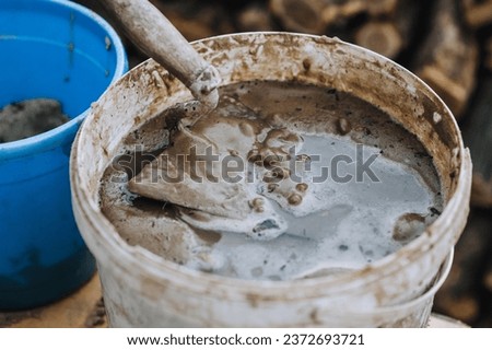 Tool, trowel in a bucket with sand, cement, water. Photography, building, concept.