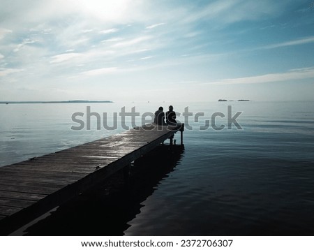 Couple of girls contemplate the sunset sitting on the dock