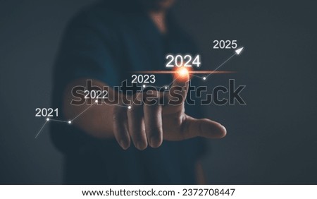Business plan and vision for 2024. Startup for business. Performance goals for growth ,Businessman uses his finger to kick the 2024 graph showing marketing strategies for the annual business plan. Royalty-Free Stock Photo #2372708447