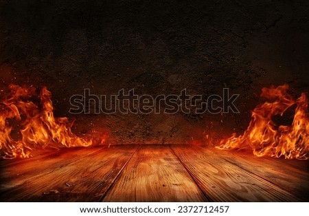 wooden table with Fire burning at the edge of the table, fire particles, sparks, and smoke in the air, with fire flames on a dark background to display products	