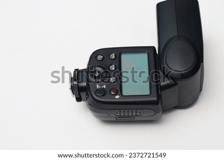 External flash light for digital cameras. Equipped with a battery inside. There is a small LCD screen to view settings. Isolated white.