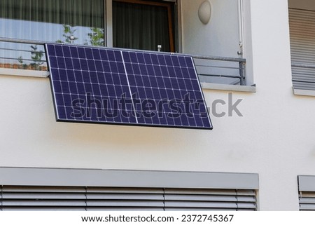Small Balcony Solar Panel energy system. Solar battery on balcony wall of modern house in Germany.  Mini PV plants generate your own electricity plug play. Royalty-Free Stock Photo #2372745367