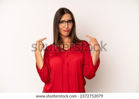 hispanic pretty woman with a bad attitude looking proud and aggressive, pointing upwards or making fun sign with hands
