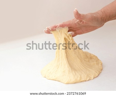 Woman's hand knead dough on a white table with copy space