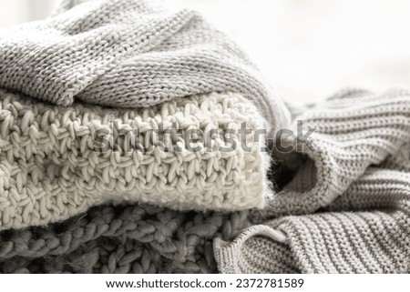 Close up of folded knitted items of grey color on a light background.