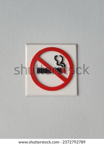 No Smoking Sign, Warning sign, No smoking in this area.
A red and white sign with a black cigarette icon on a white wall in a room.