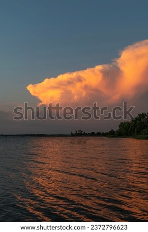 Large cloud with orange hue during sunset at North Turtle Lake in Minnesota, USA.
