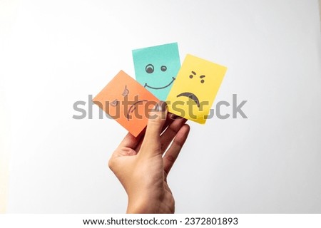 Woman hand holding multiple mood smiley sticky notes on over white background
