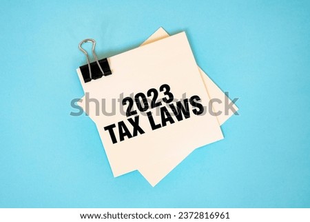 Text 2023 TAX LAWS on sticky notes with copy space and paper clip isolated on red background. Finance and economics concept.