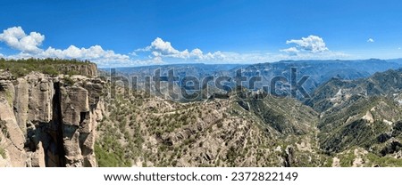 An expansive panoramic shot capturing the majestic Copper Canyon from El Divisadero Station in Chihuahua, Mexico, displaying the canyon's intricate network of ravines under a vast sky.
