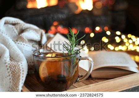 Hot toddy tea mocktail cocktail by the fire with book and blanket in background Royalty-Free Stock Photo #2372824575