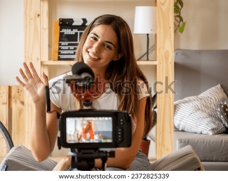 Young woman recording a video for social networks greeting the camera in an apartment
