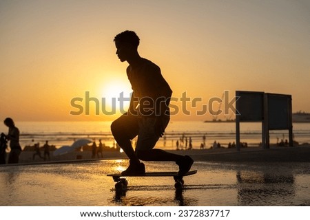 Surf skater training surfing moves near the beach at sunset. Royalty-Free Stock Photo #2372837717