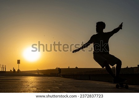 Surf skater training surfing moves near the beach at sunset. Royalty-Free Stock Photo #2372837723