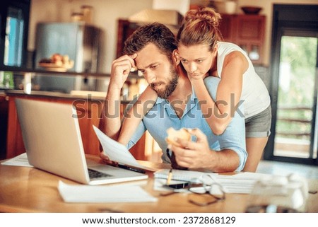 Young couple embracing each other during a financial crisis in the kitchen of their home Royalty-Free Stock Photo #2372868129