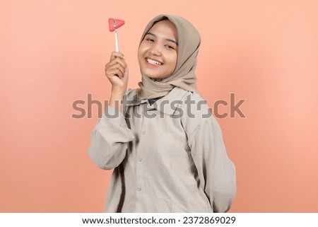 beautiful young Asian woman is holding a reflex hammer next to her head while smiling with teeth showing