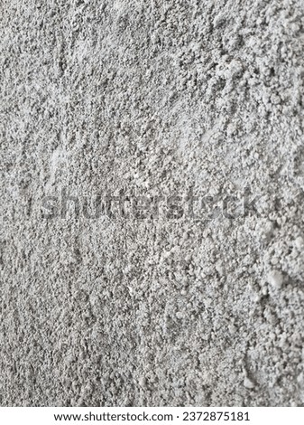 The rough texture of sand and cement on the wall.