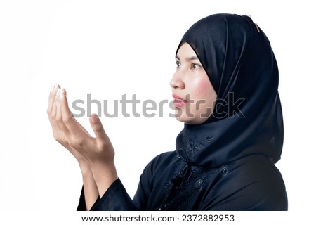 The image of an Asian Muslim woman in the Islamic religion in hijab in black color. She was praying of respect for God.