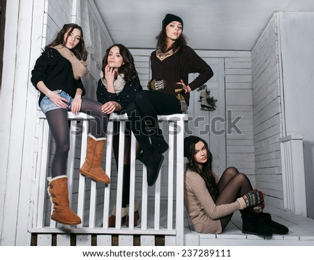 Four stylish models posing sitting on the fence. Christmas background