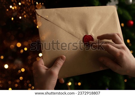 A child holds in his hands an envelope with wishes from Santa Claus. Wish list for Santa Claus inside 