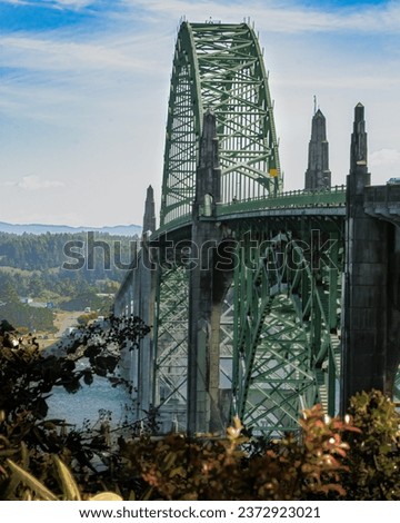 Yaquina Bay Bridge with blue skies and fall colored leaves. Picture taken from a distance and at an angle
