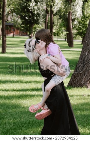 Girl hugging mother in spring or summer park. Family relaxing outdoors. Mothers day. Close up.